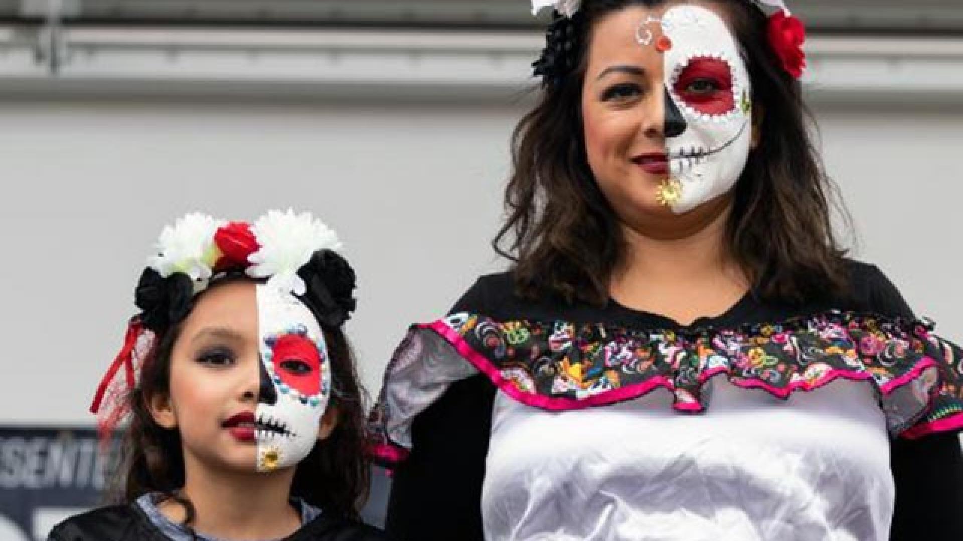 A daughter and a mother dressed alike in costumes for a Dia de Los Muertos event.