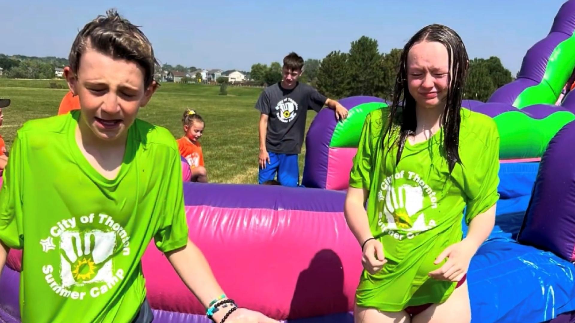 Young boy and girl in green near inflatable slide