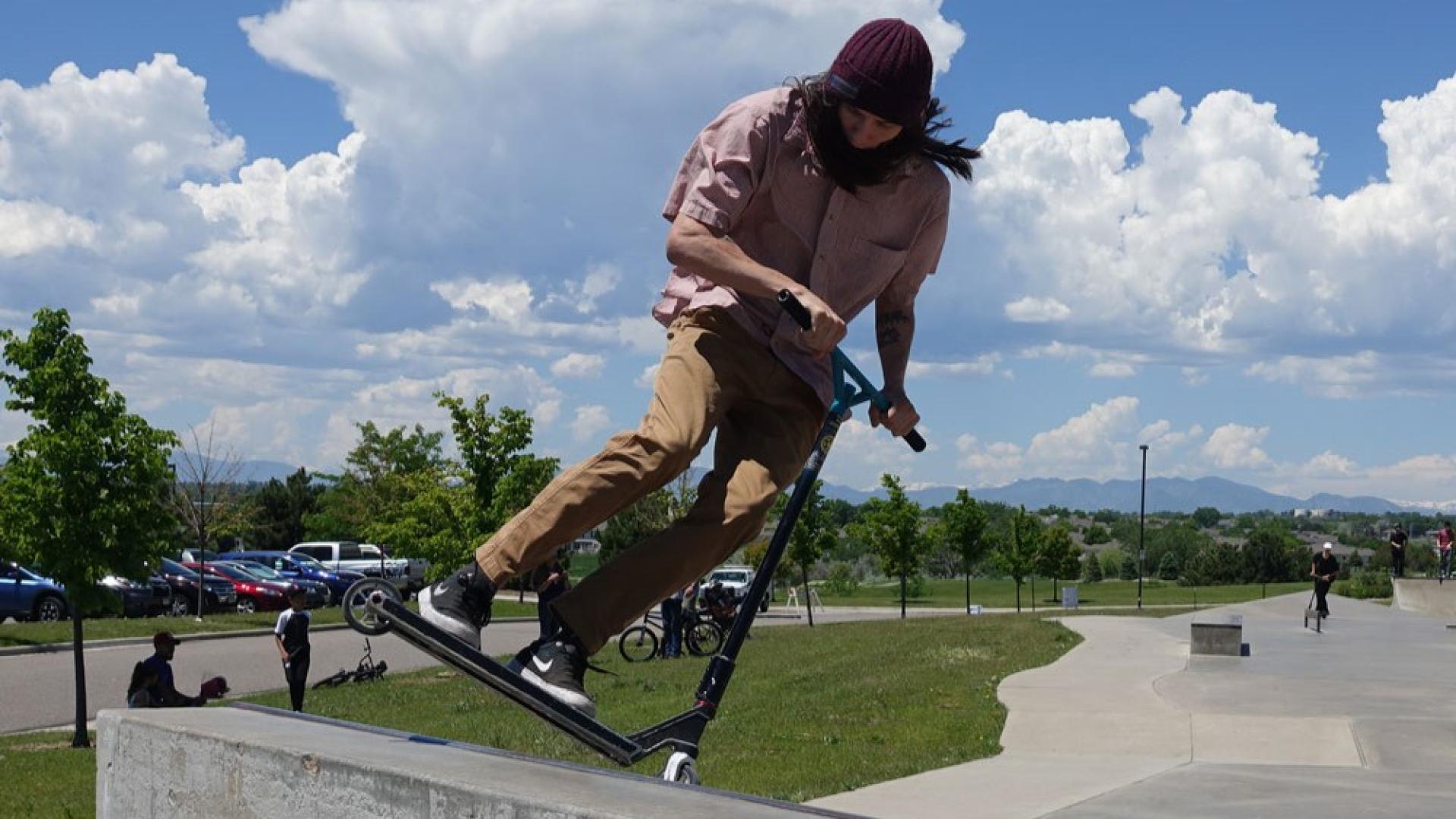 Young man performing a trick on the scooter at Carpenter Park Skate Park
