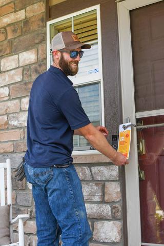 Man placing a door tag on a door.